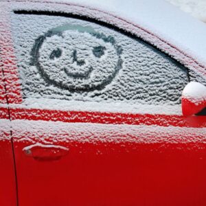 smiley face on car door window in the snow