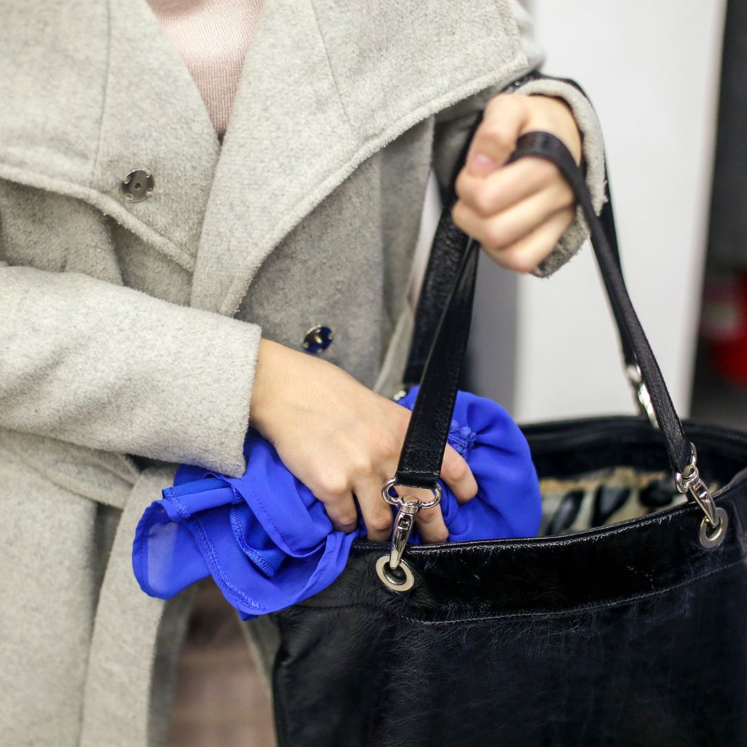 Woman putting a blue item into her purse sneakily. 