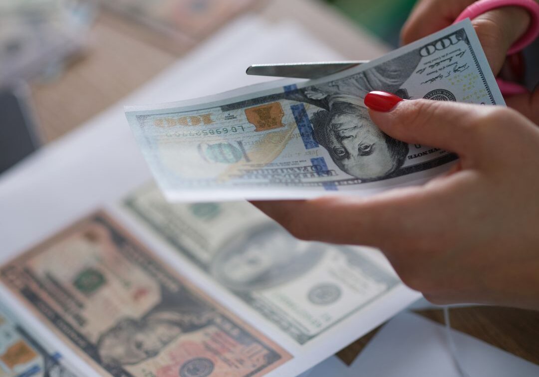a woman cutting counterfeit bills